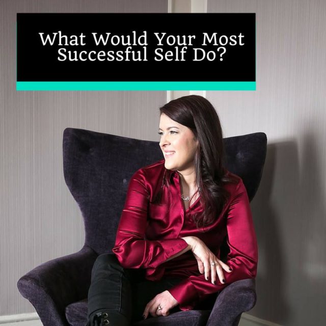 happy woman in a shiny red silk button down shirt and black pants sitting in a purple velvet chair looking to the side and feeling very successful